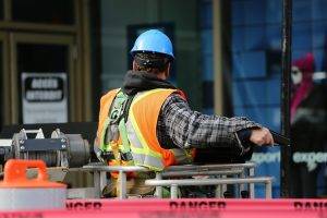 worker with blue helmet in front of danger tape