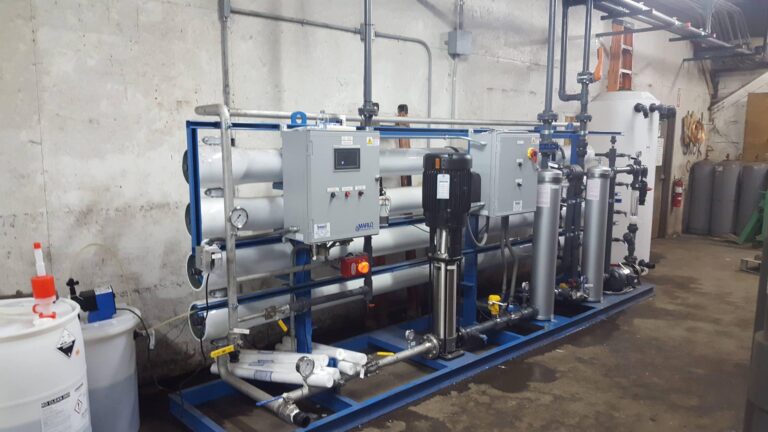 High-capacity water treatment system engineered by Besco Commercial for Alexander Chemical Corporation. Focus on the blue framework with mounted controls.