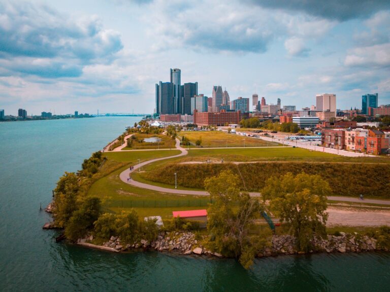 Detroit, Michigan cityscape showcasing a large park and city skyline on a sunny day with blue clouds.