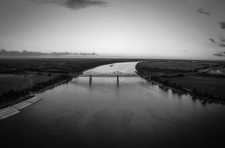 Black and white photo depicting a river in Toledo, Ohio with bridge spanning the length of the water.